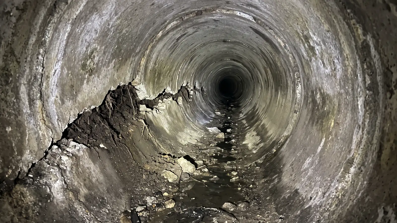 Before: a sewer pipe with a long crack and debris
