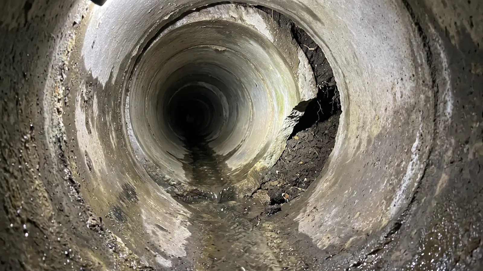 Before: a sewer pipe joint where one section has slipped, leaving a ledge and a gap